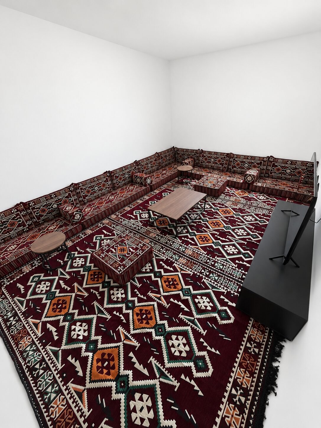 Aousserd deep burgundy Sahrawi majlis with a matching rug in a white room