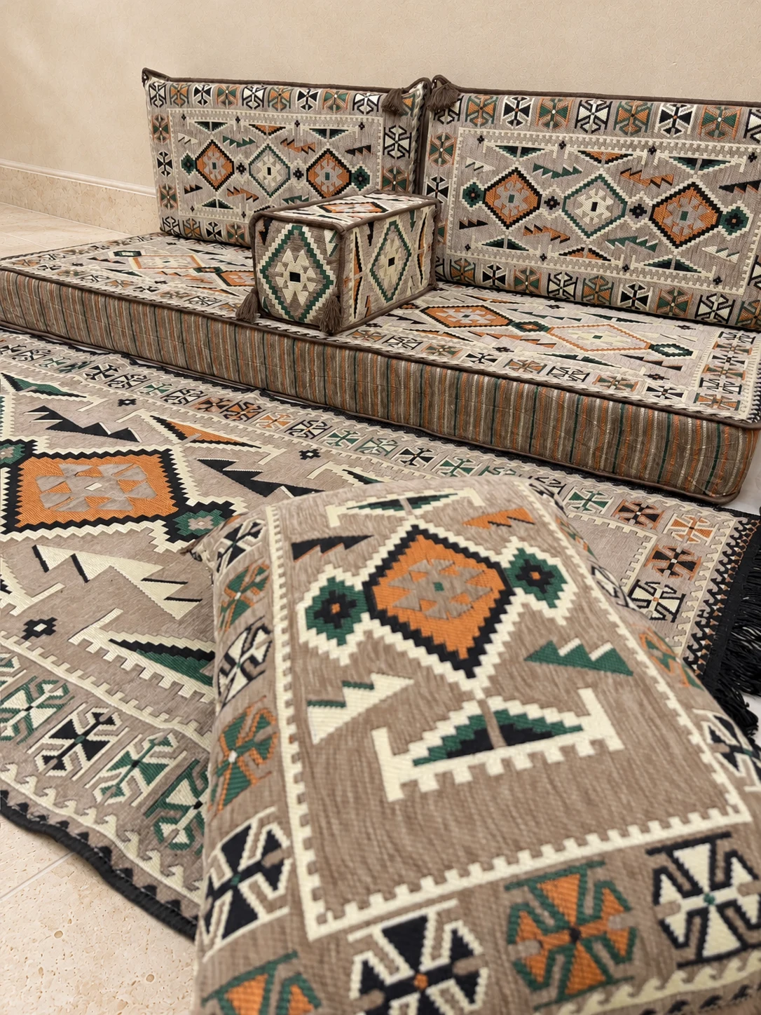 Close-up of a floor cushion of the beige Sahrawi single majlis set, with the seat and armrest behind