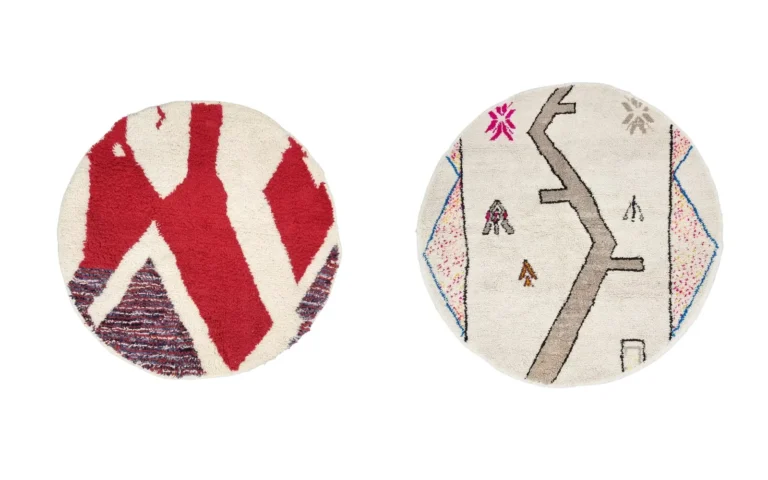 Two round handmade Moroccan wool rugs: one with bold red abstract shapes on ivory, one in ivory with taupe symbols and blue-edged side panels.
