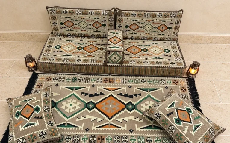Beige Sahrawi majlis floor seating: a floor seat with back cushions, an armrest, floor cushions and a matching rug.