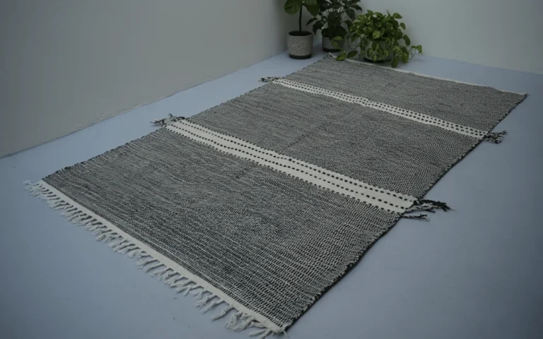 Zanafi black and ivory handwoven wool flatweave rug with fringe, laid flat on a floor