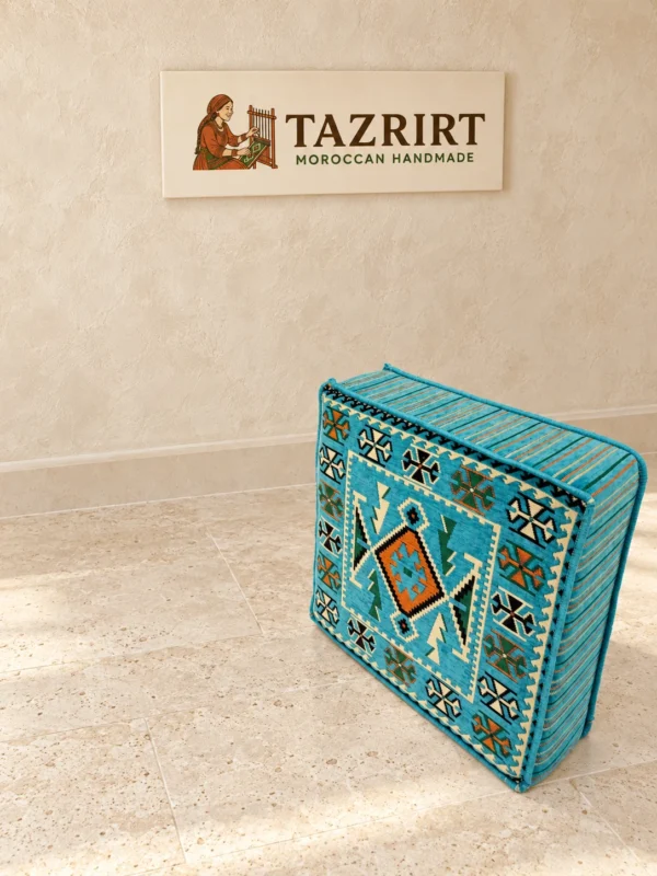 Turquoise kilim floor pouf standing upright, showing its patterned top and striped, piped sides.