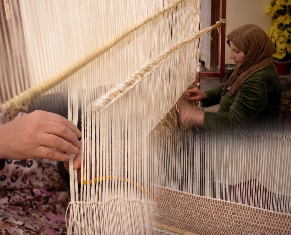 An artisan weaving a wool rug by hand at a traditional loom