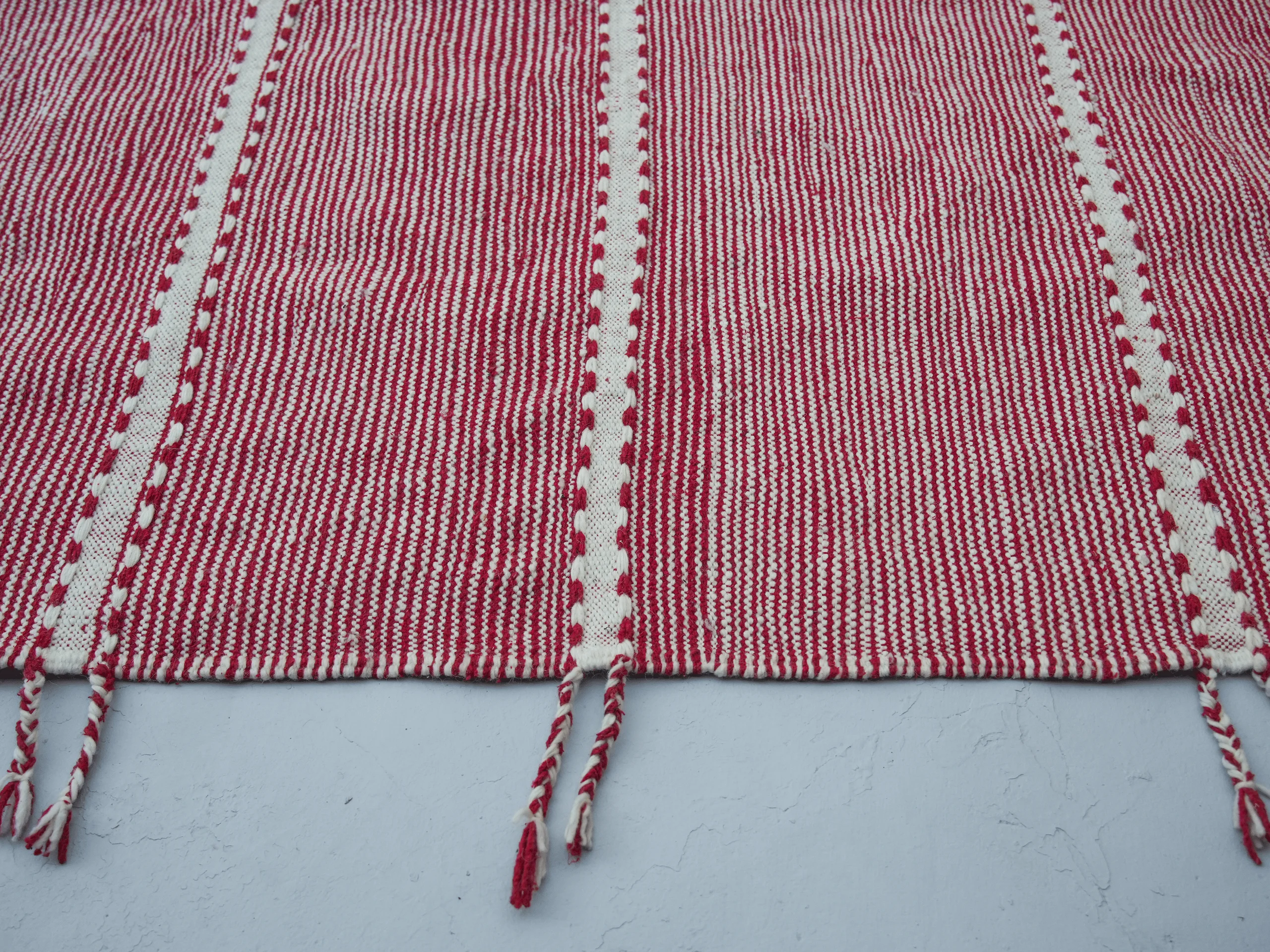 Close-up of fine red and ivory stripes, decorative ivory bands and subtle geometric lines on a Zanafi rug.