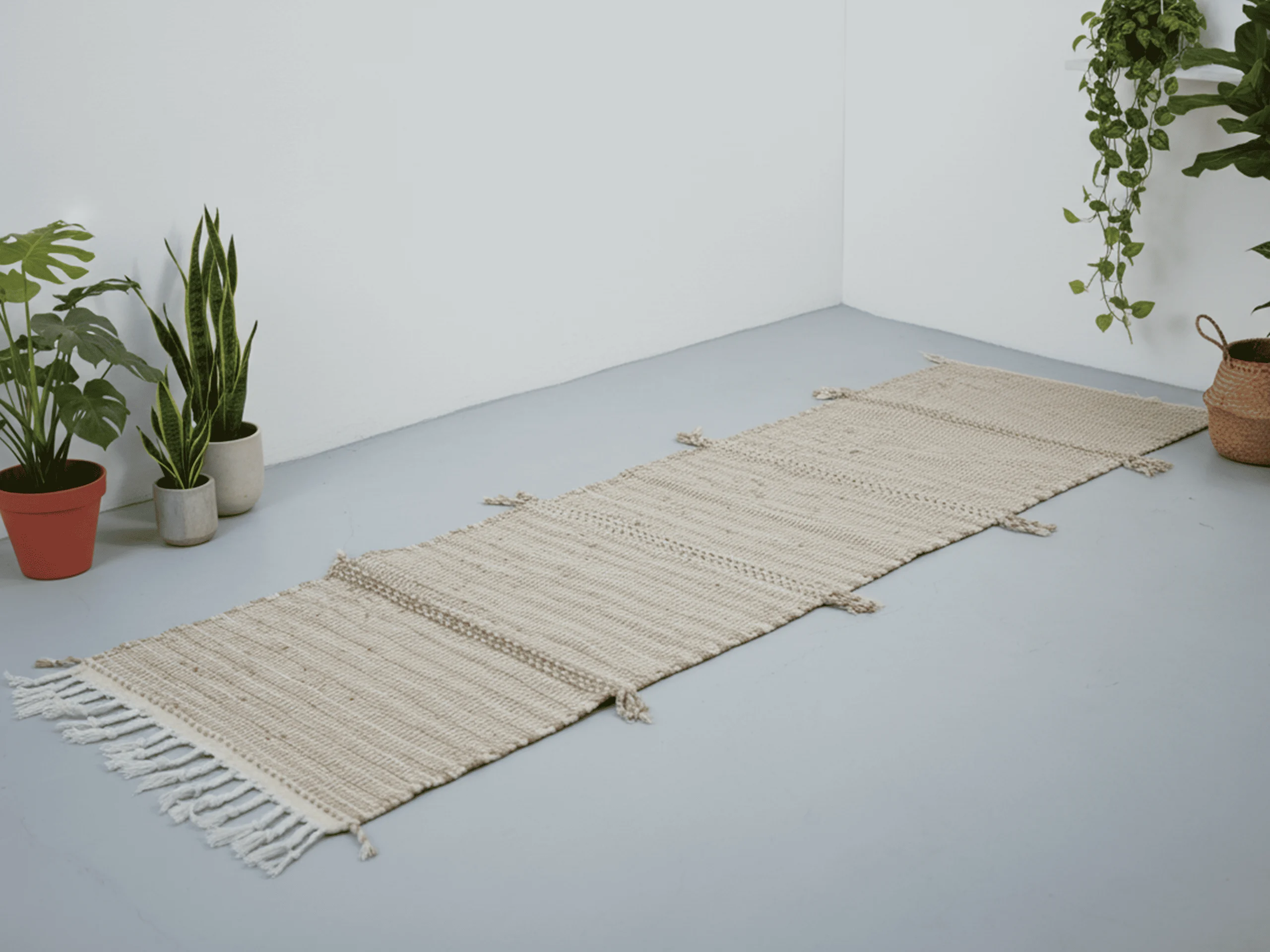 Beige Zanafi Moroccan wool runner laid flat on the floor, showing its long narrow shape and ivory fringe.