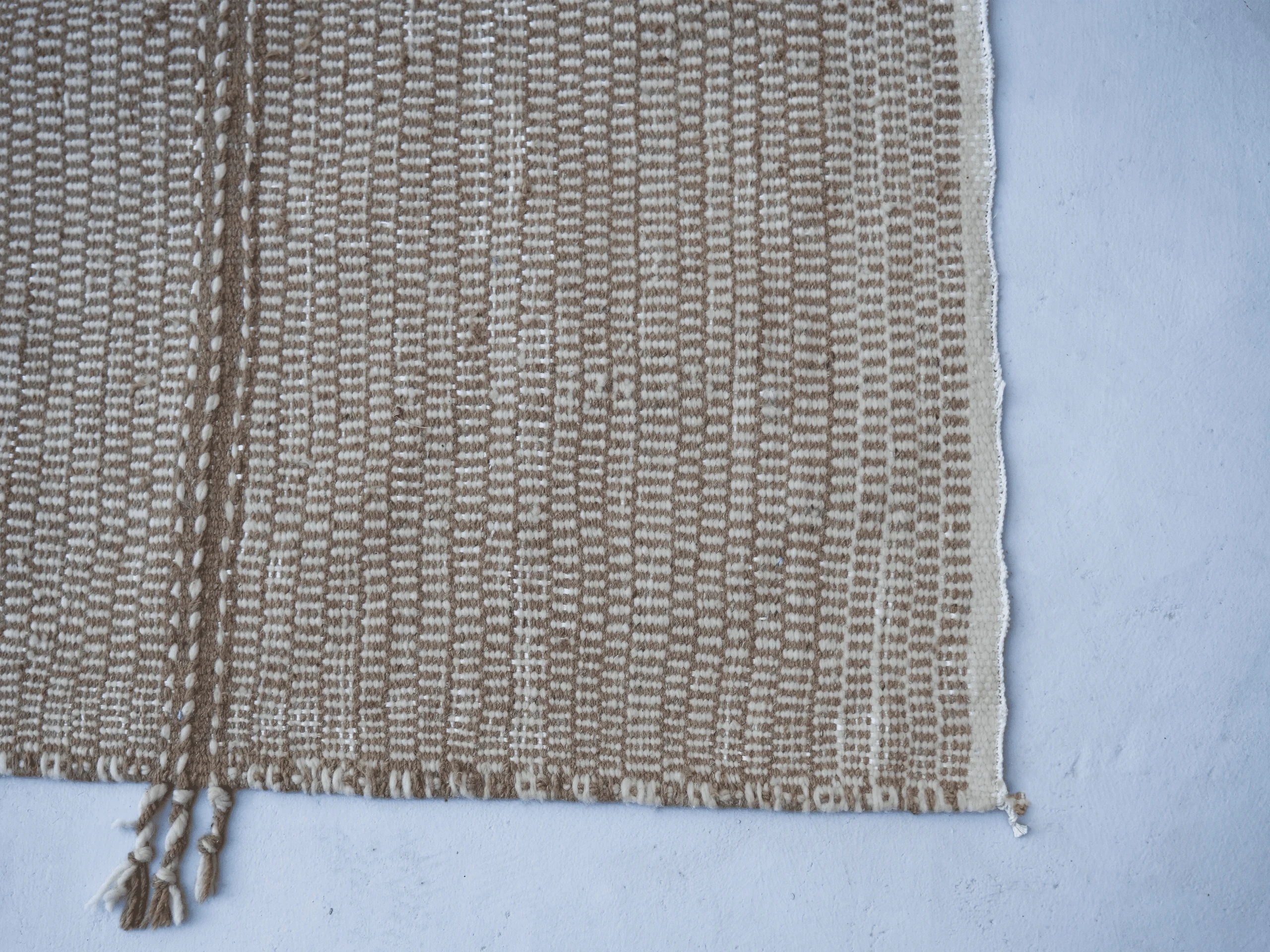 Close-up of the beige and ivory flatweave texture and a decorative woven band on a Zanafi wool runner.