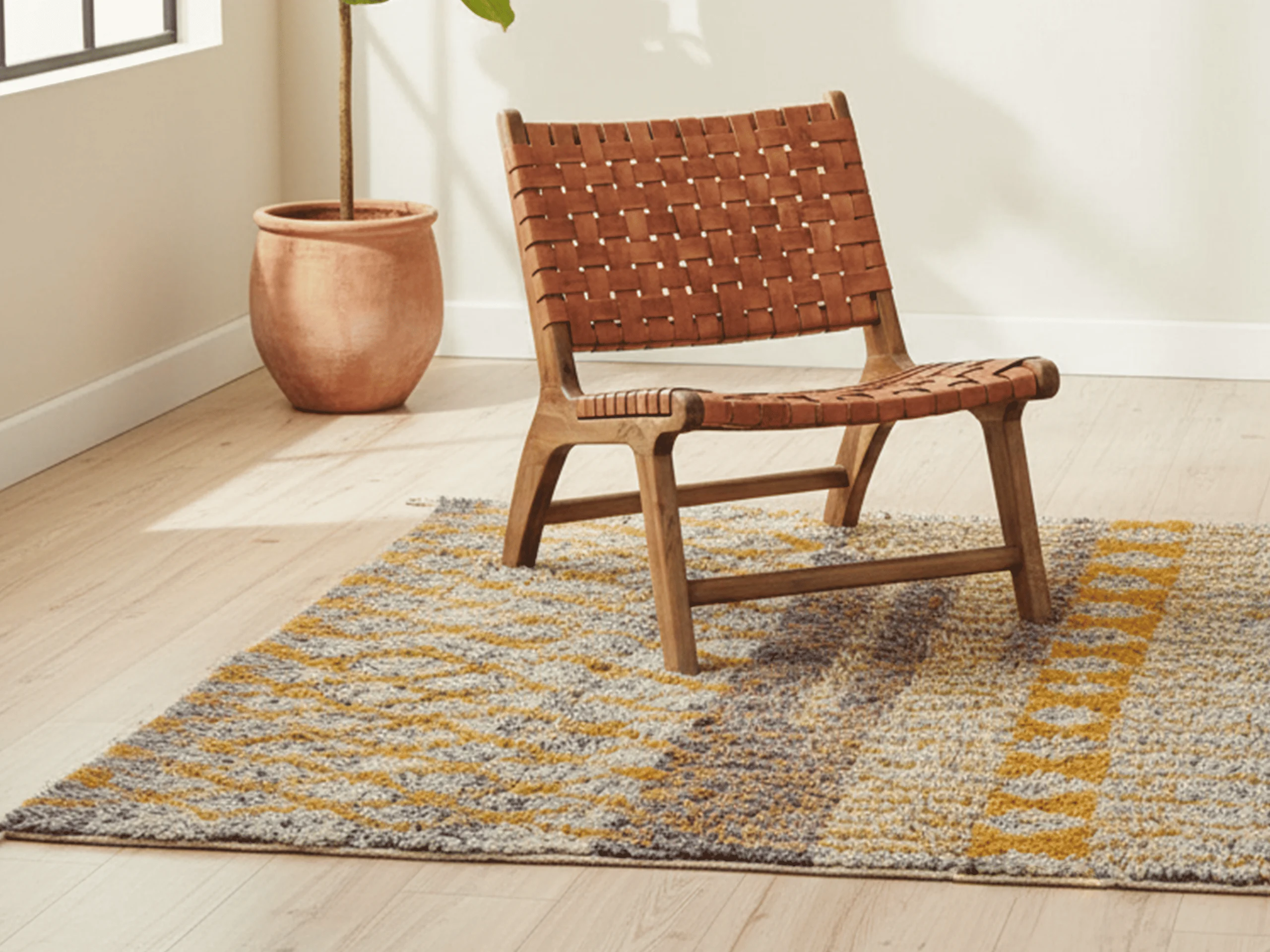 Woven leather lounge chair on a mustard and gray Azilal-style Moroccan wool rug.