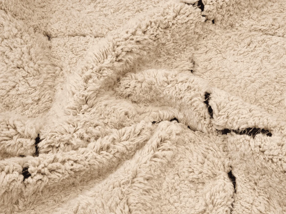Macro view of the shaggy cream wool pile crossed by fine black lines.