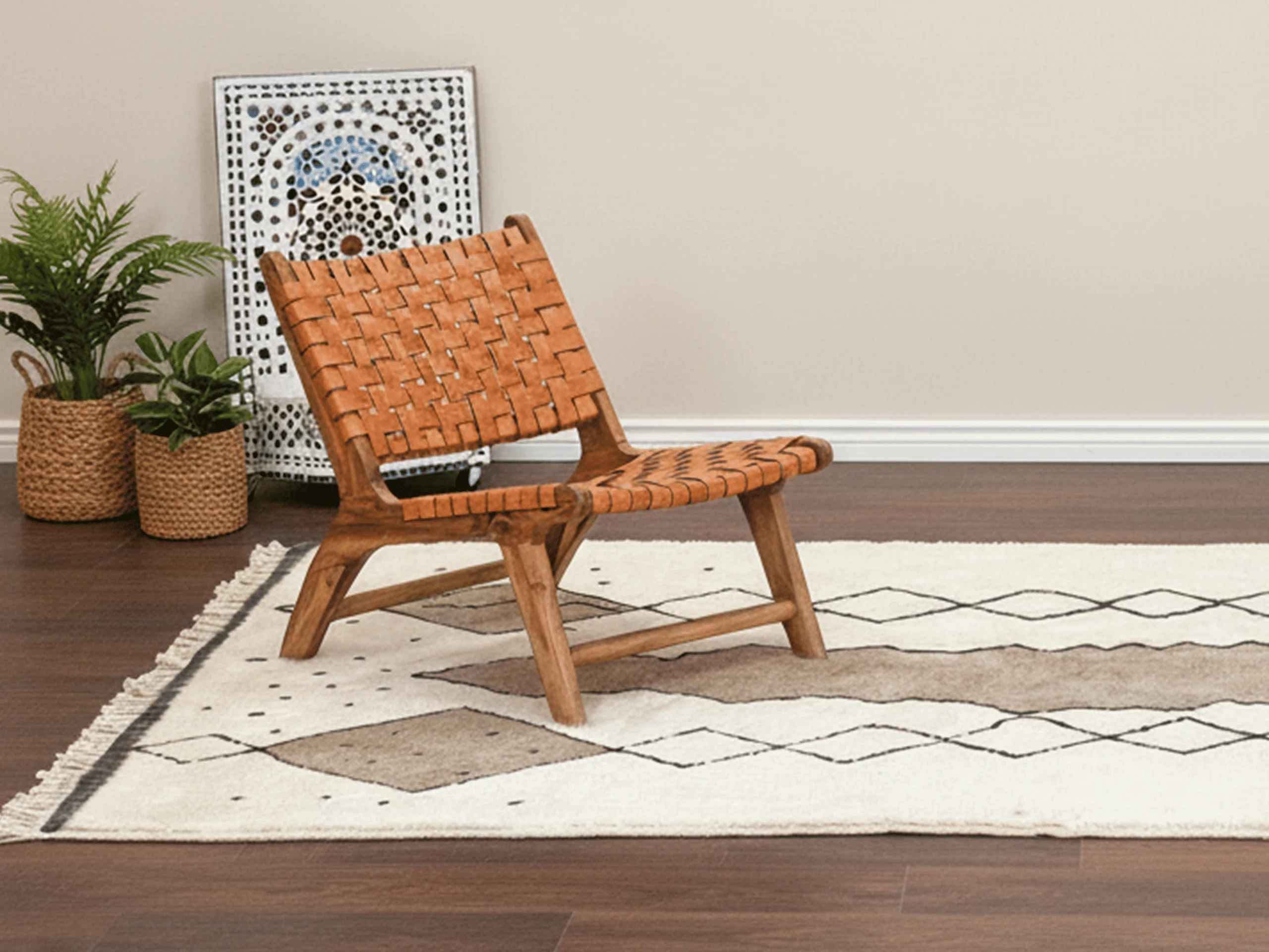 Ivory and taupe rug with diamond chains under a woven leather lounge chair beside plants.