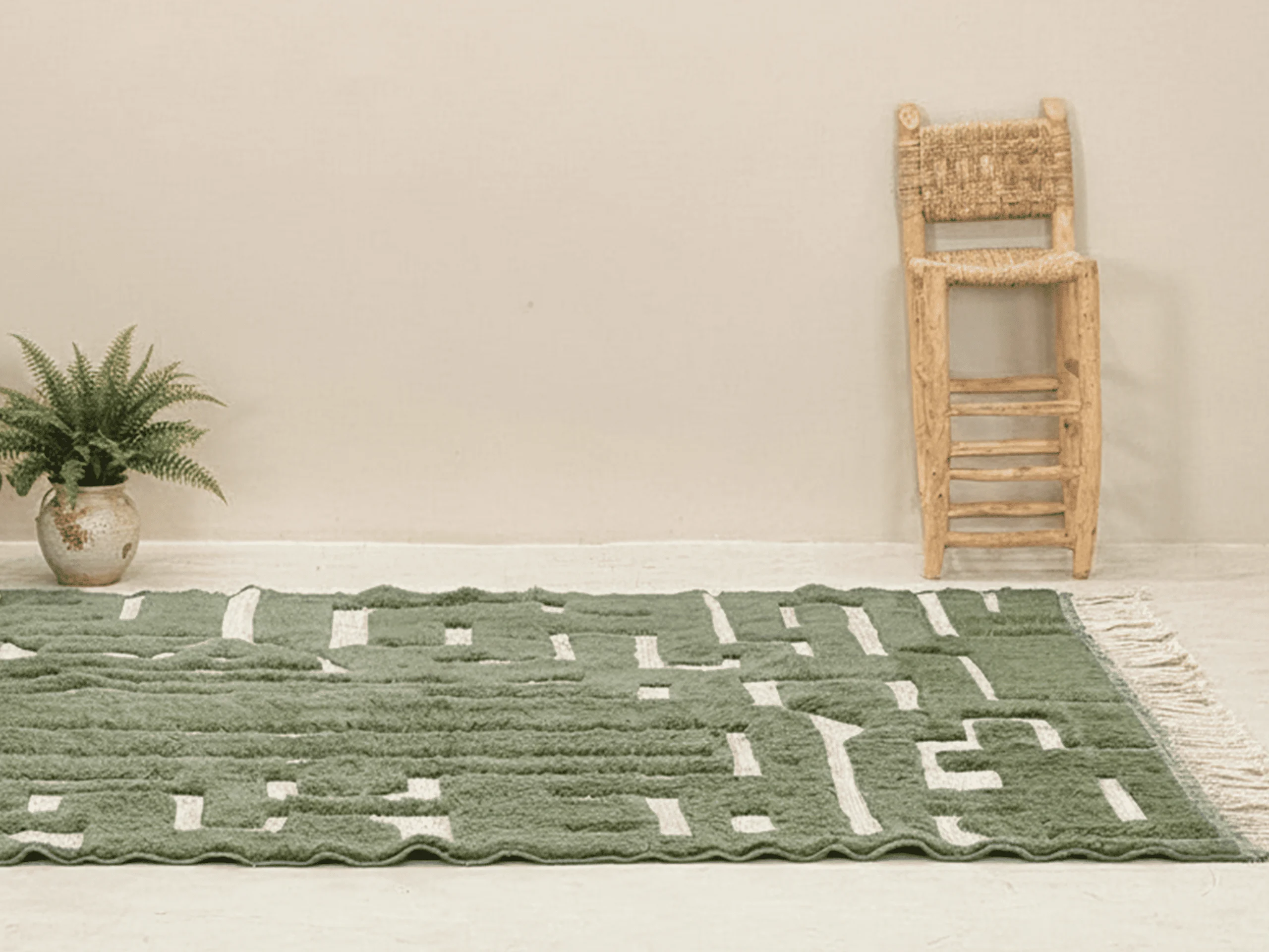 Green relief maze rug on a light floor beside a woven stool and a potted plant.