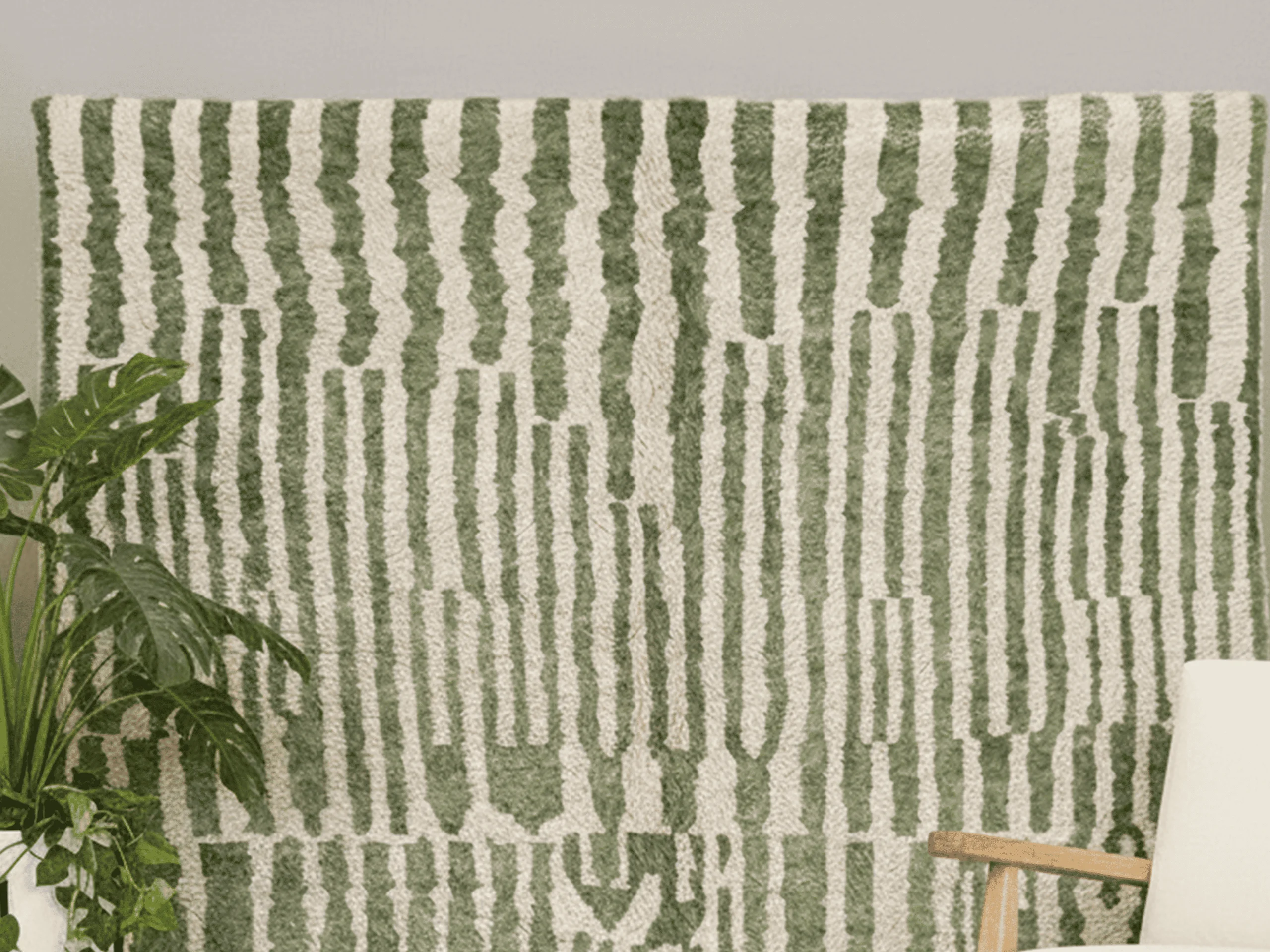 Close-up of green and ivory broken stripes with small zigzag motifs in thick wool pile.