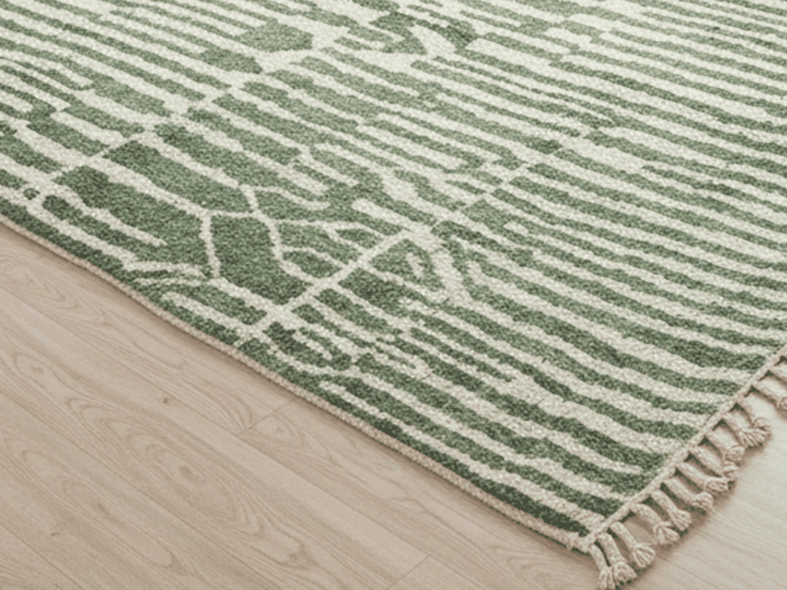Corner of the green striped rug showing the ivory lines, bound edge and braided fringe on a pale floor.