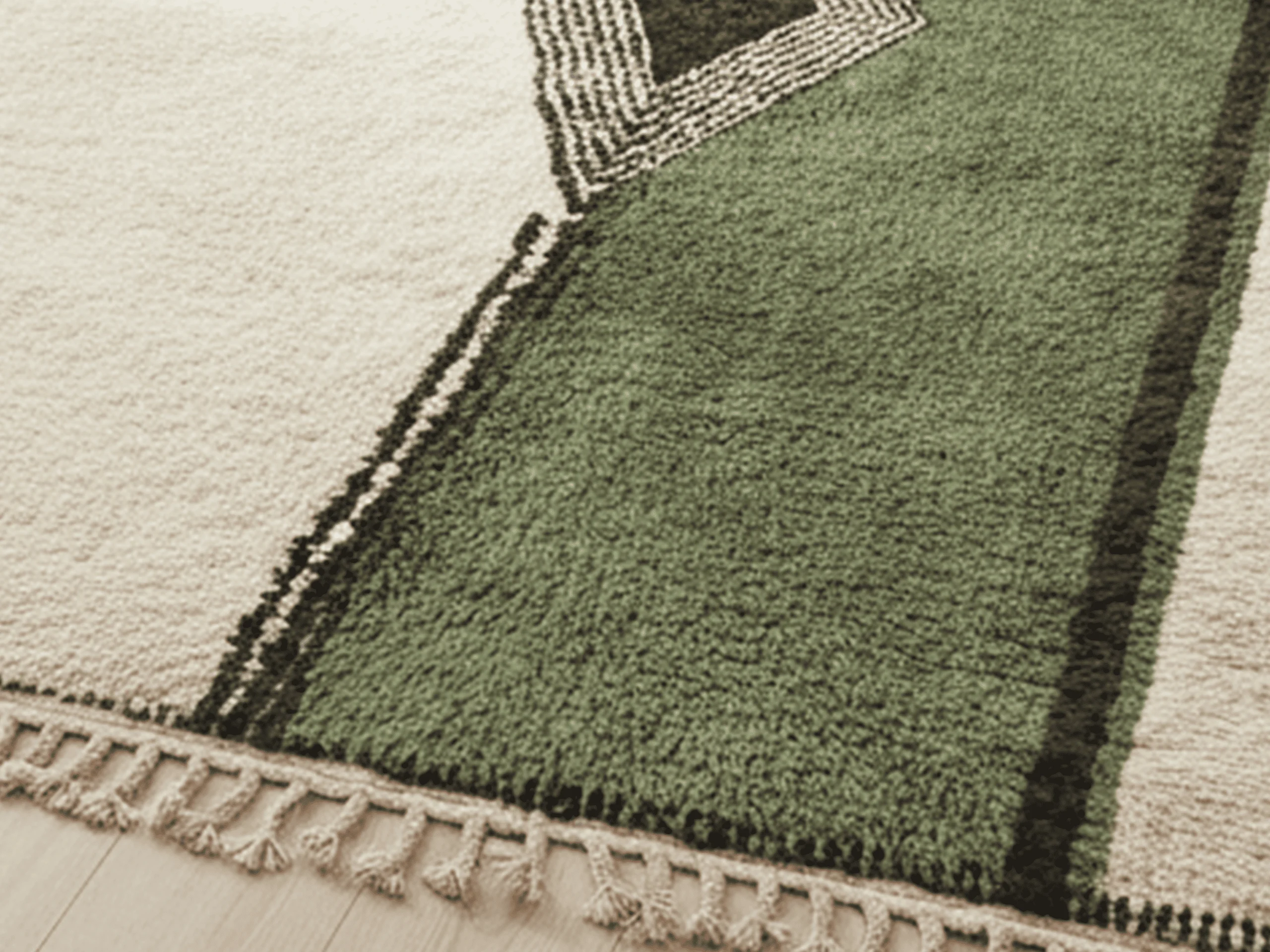 Close-up where ivory pile meets green pile, with a black line, the stippled diamond edge and fringe.