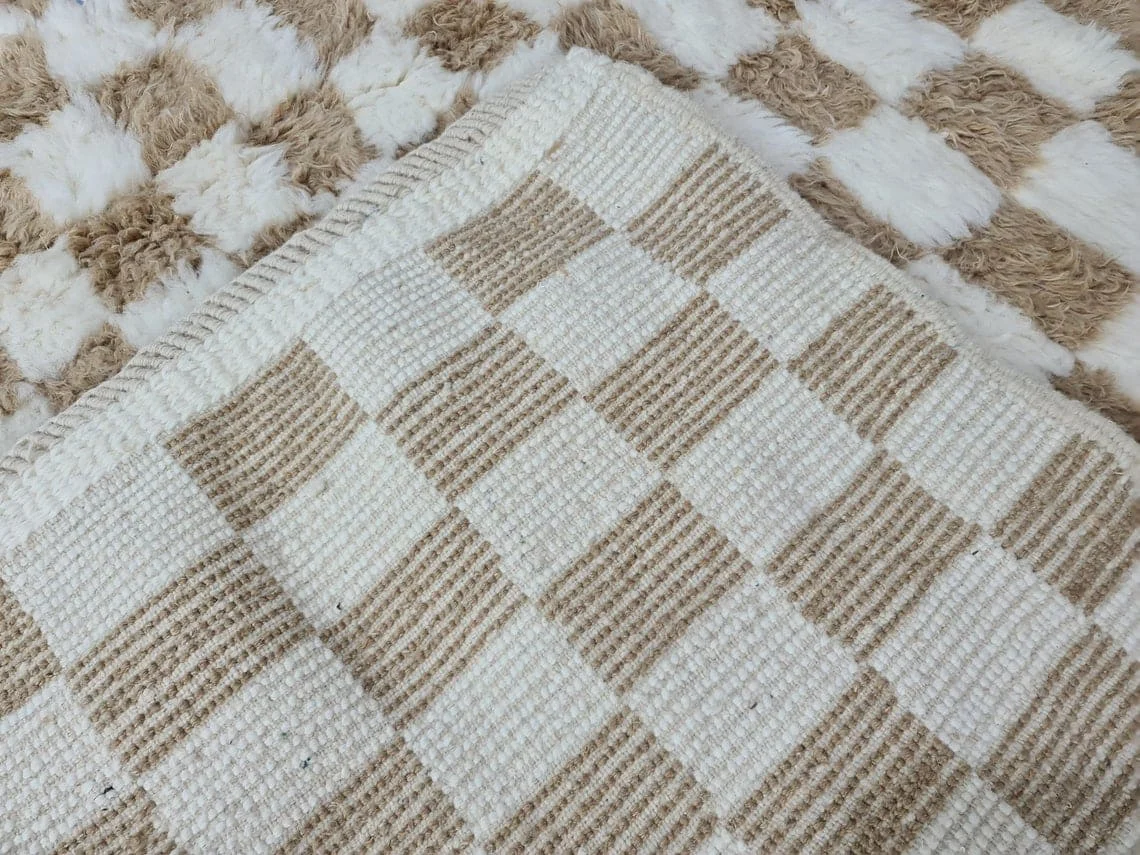 Close-up of the flat-woven reverse in beige and ivory checks, folded over the shaggy front.