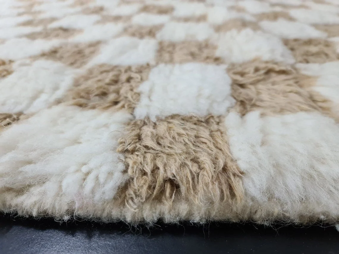Low side view of the pile showing long beige and ivory tufts at the rug's edge.