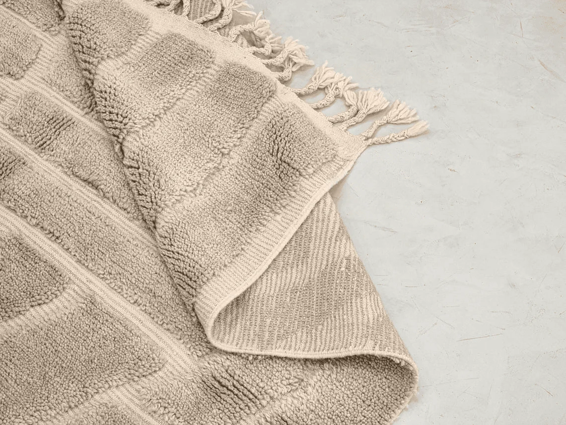 Close-up of a folded corner with raised gray bands, the flat-woven reverse and cream tassels.
