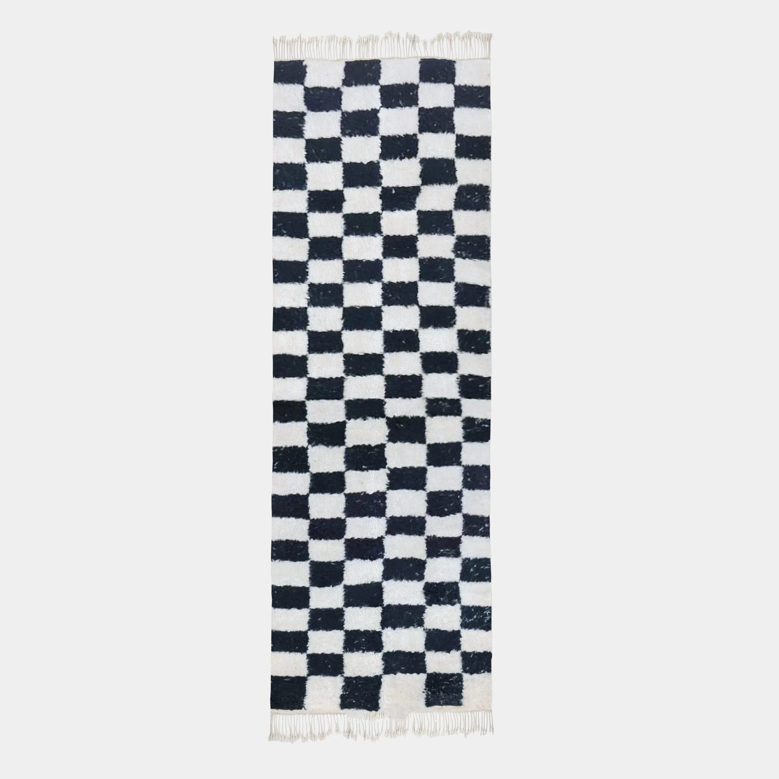 Long black and ivory checkerboard wool runner on a light gray background with fringe at both ends.