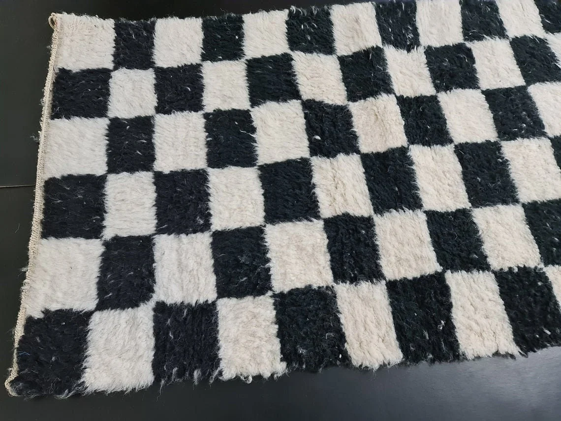 Angled close view of the black and ivory checkered runner on a dark floor, showing the shaggy pile.