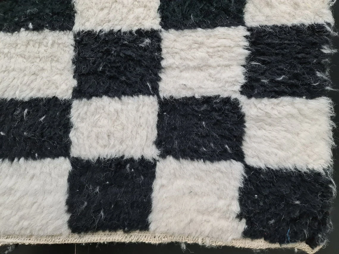 Close-up of large black and ivory squares in long wool pile along the runner's bound edge.