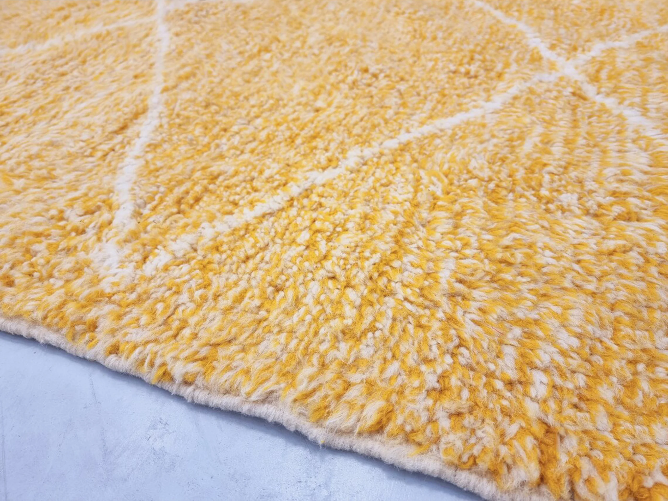 Close-up of golden yellow wool pile crossed by thin ivory diamond lines.
