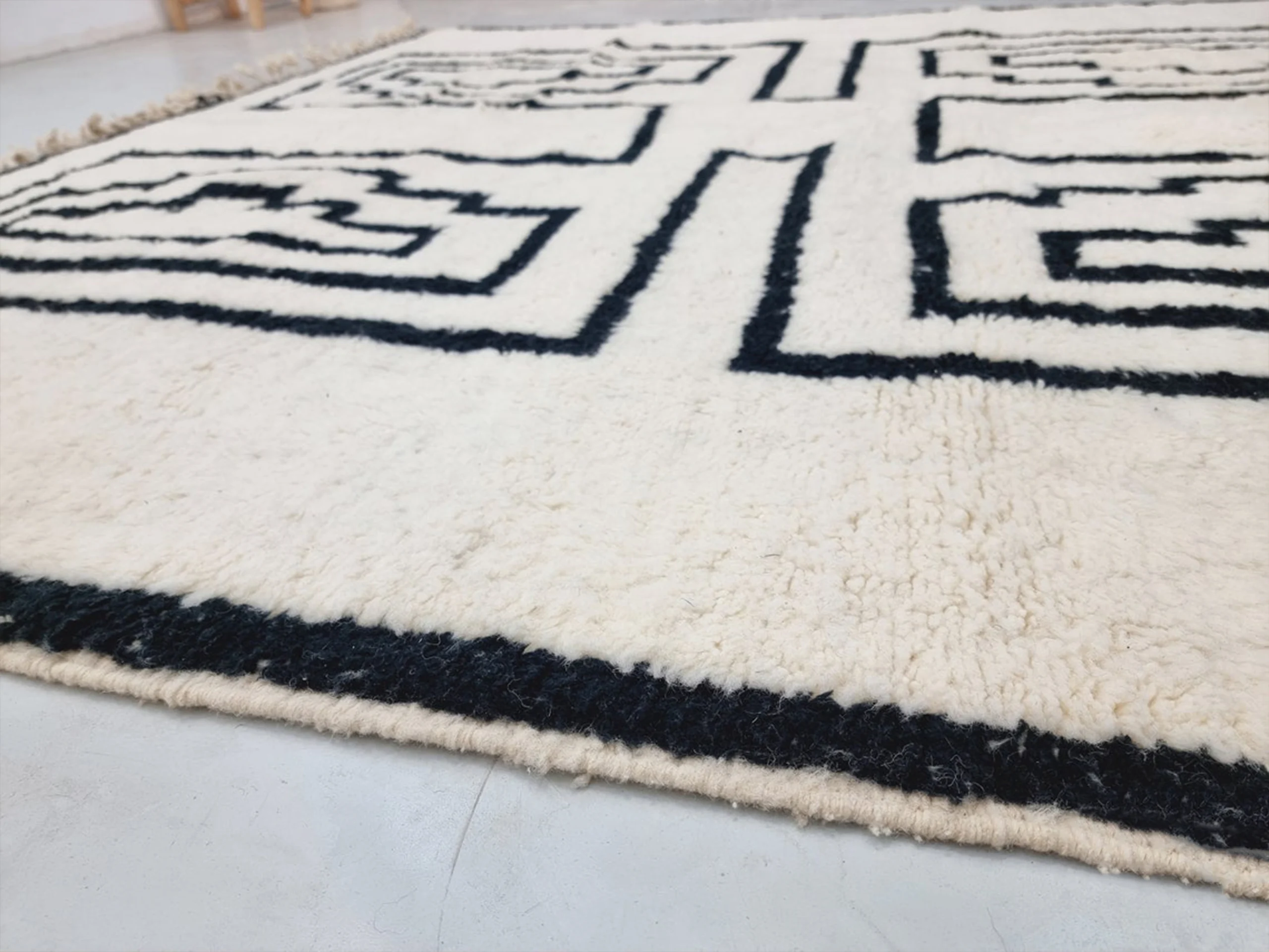 Close-up of dense ivory pile with thick black lines and the black border at the rug's edge.