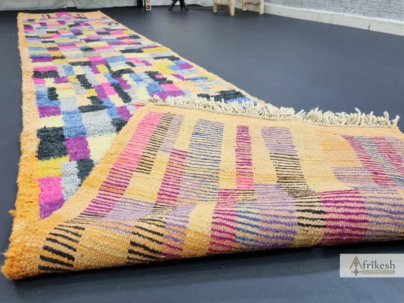 Folded end of the runner showing the apricot flat-woven reverse with colored stripes and fringe.