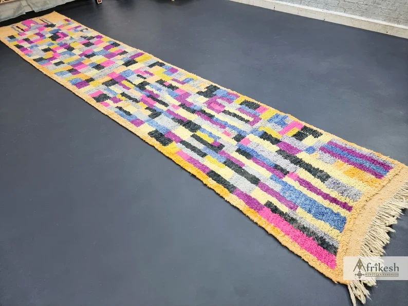 Angled view of the full multicolor patchwork runner laid on a dark floor.