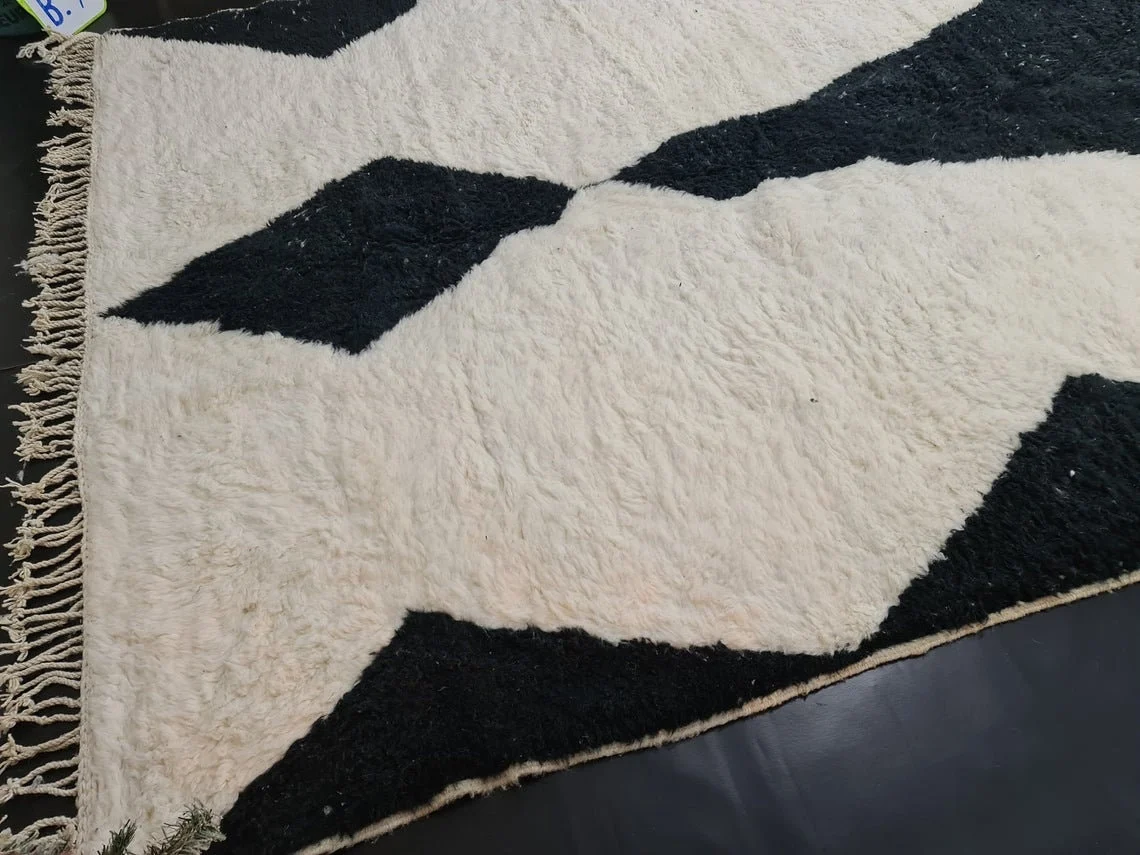 Angled close view of a black diamond on ivory pile with ivory fringe along the edge.